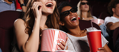 Cheerful friends sitting in cinema watch film