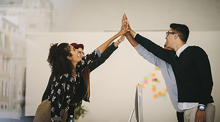 Business colleagues giving high five and celebrating in office